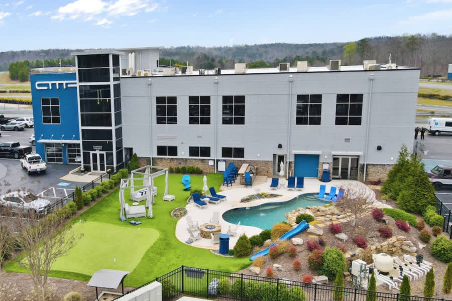 The AMP clubhouse from the air, with the pool, fire pit, putting green and lawn laid out behind it and the circuit beyond