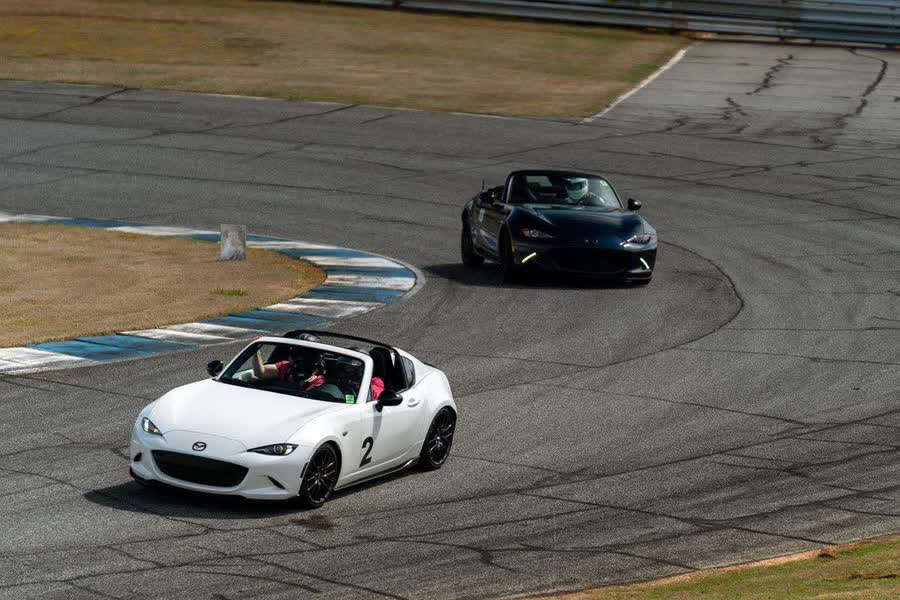 Two Mazda MX-5s running in formation through a corner at Atlanta Motorsports Park